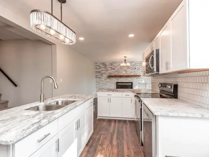 A kitchen with white cabinets , granite counter tops , stainless steel appliances and a sink.