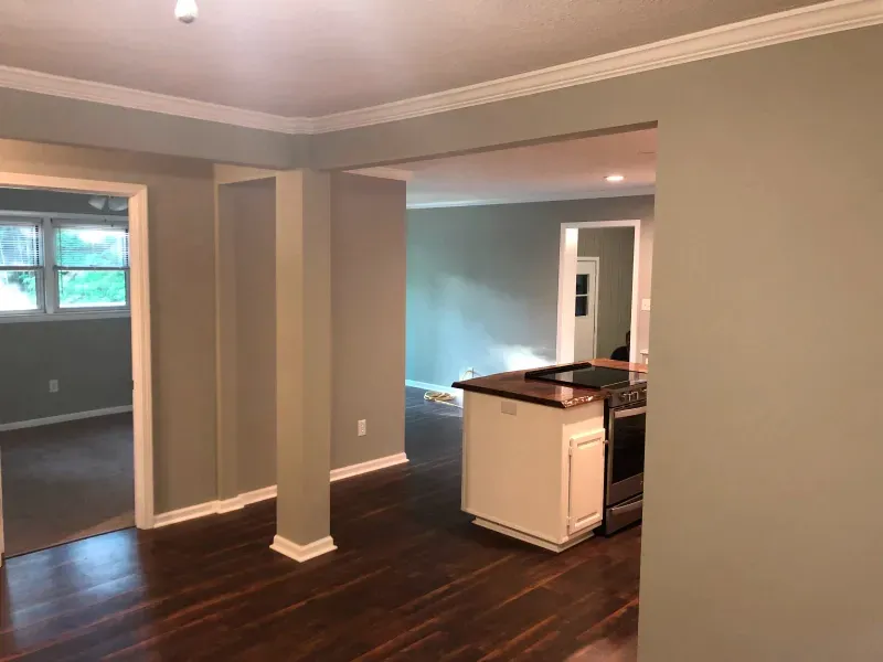 An empty room with a kitchen in the background