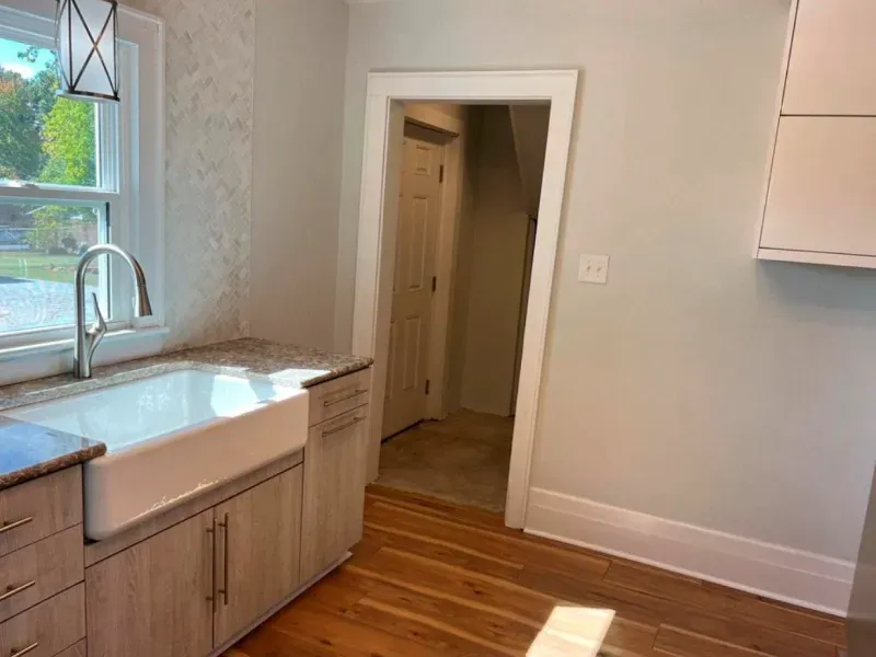 A kitchen with a sink , cabinets , and hardwood floors.