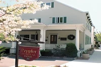 Peppler Funeral Home, white building with porch, sign in front, leafy tree.