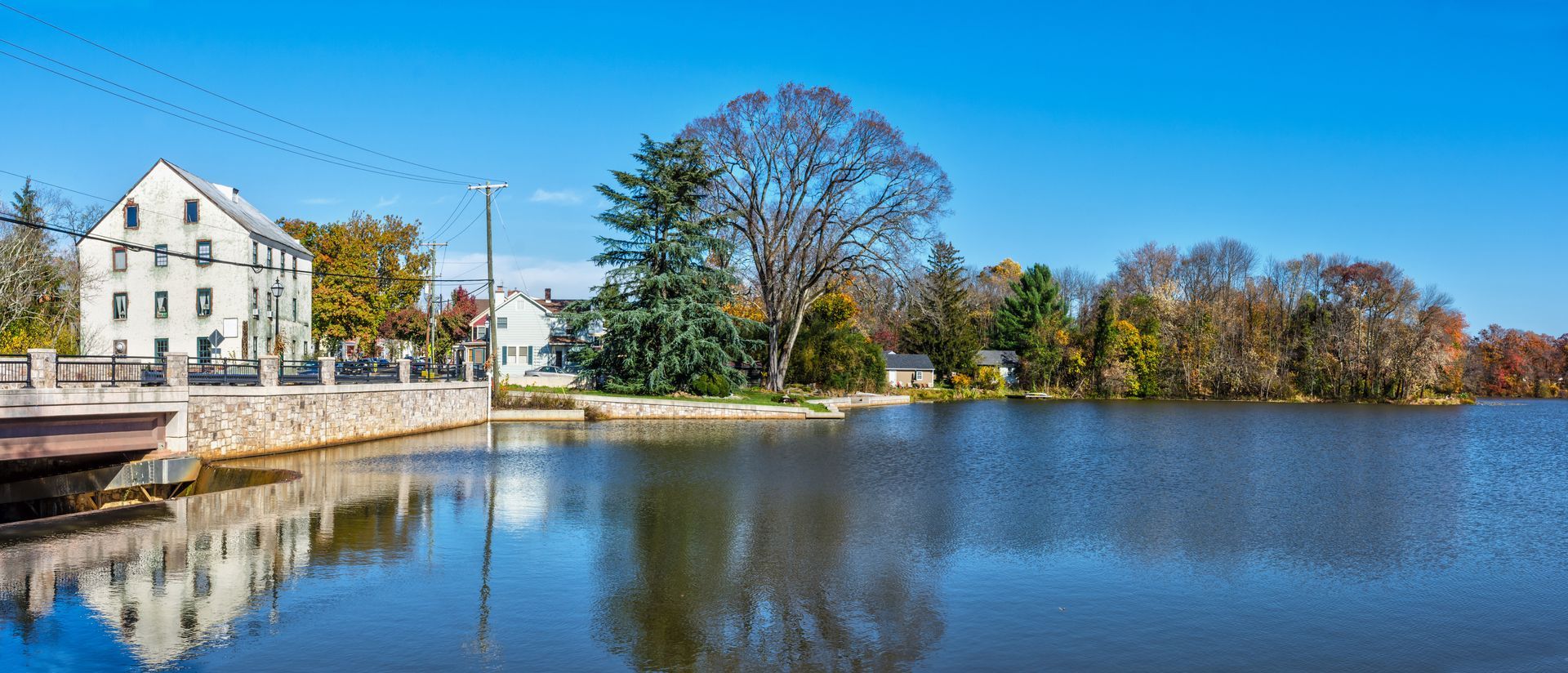 Lake with buildings and trees under a clear blue sky.