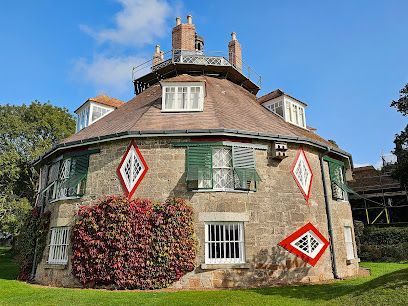 Round, stone building with red diamond accents, green shutters, and an observation deck.