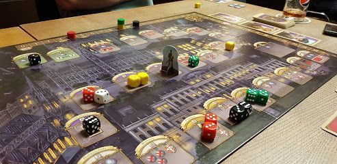 Board game in play with dice and colored tokens on a city-themed board.