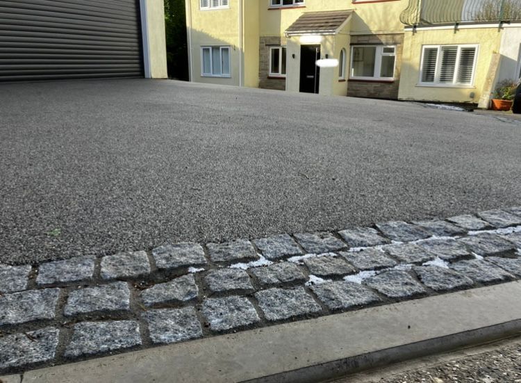 Grey resin driveway with grey block paving borders.
