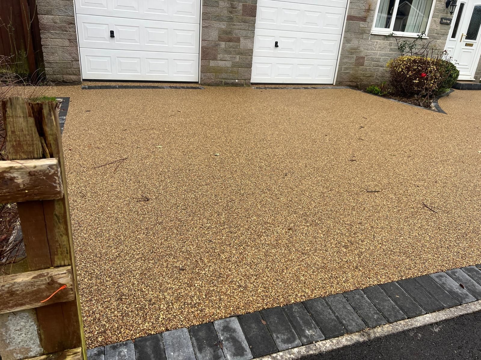 A gravel driveway in front of a house with two garage doors.