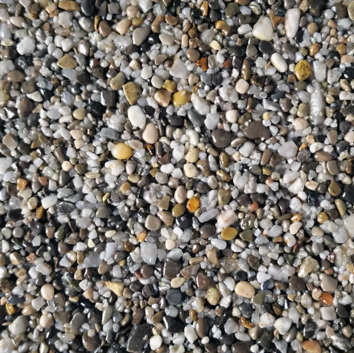Close-up of a speckled gravel surface; varying sizes of polished, colorful stones.