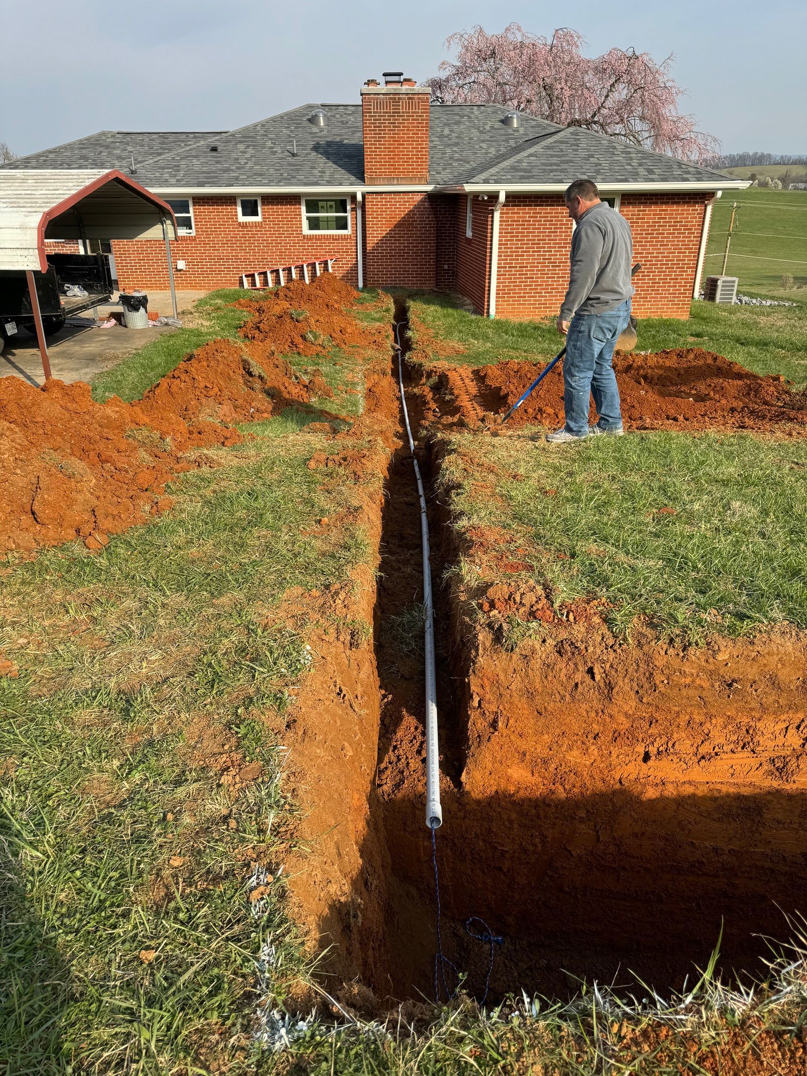 A man is digging a hole in the dirt in front of a house.