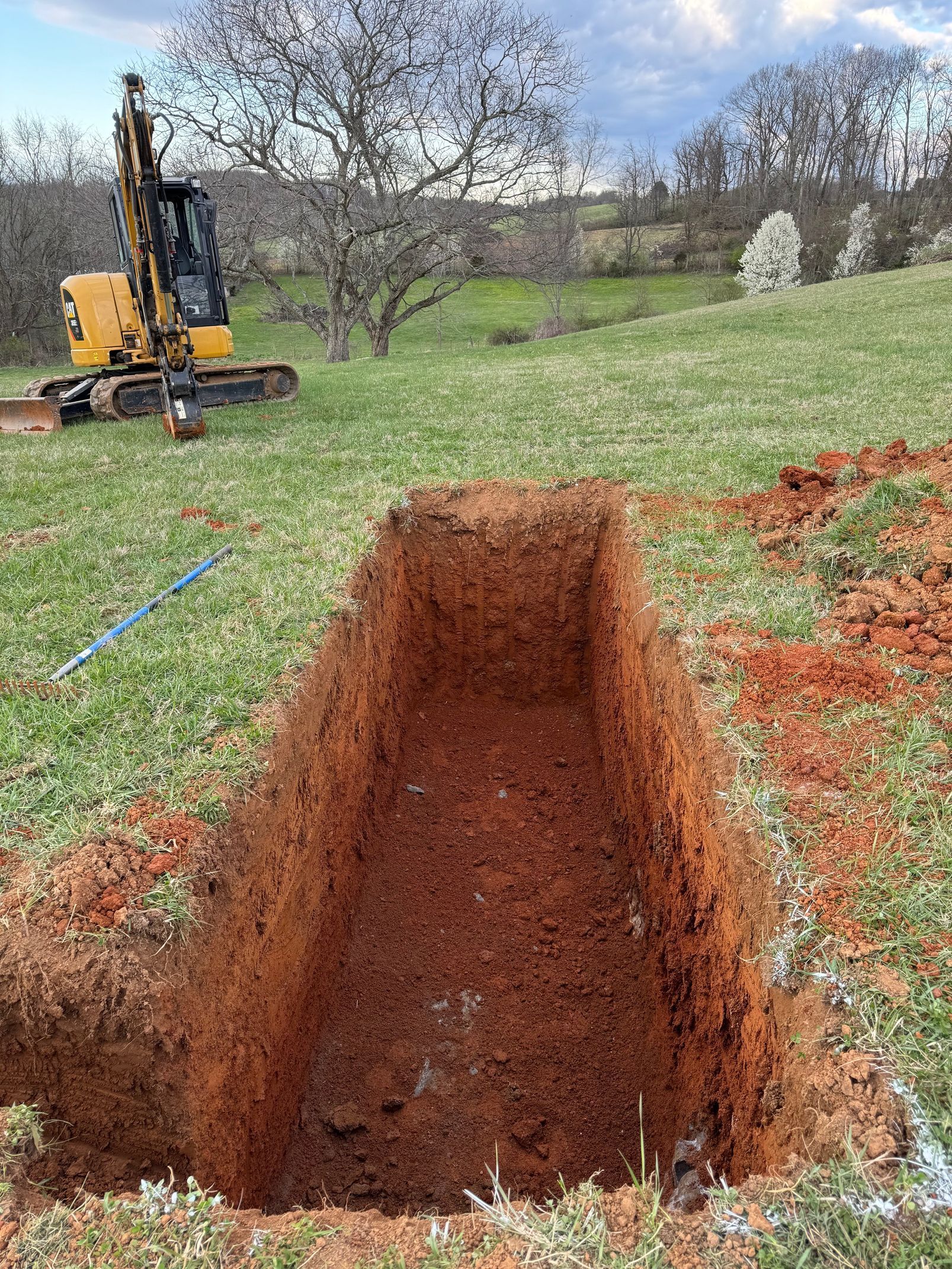 A large hole in the ground with a bulldozer in the background.