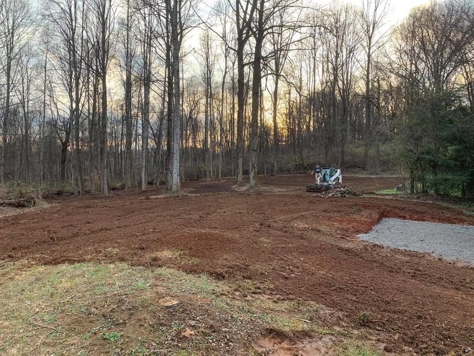 A large dirt field with trees in the background.