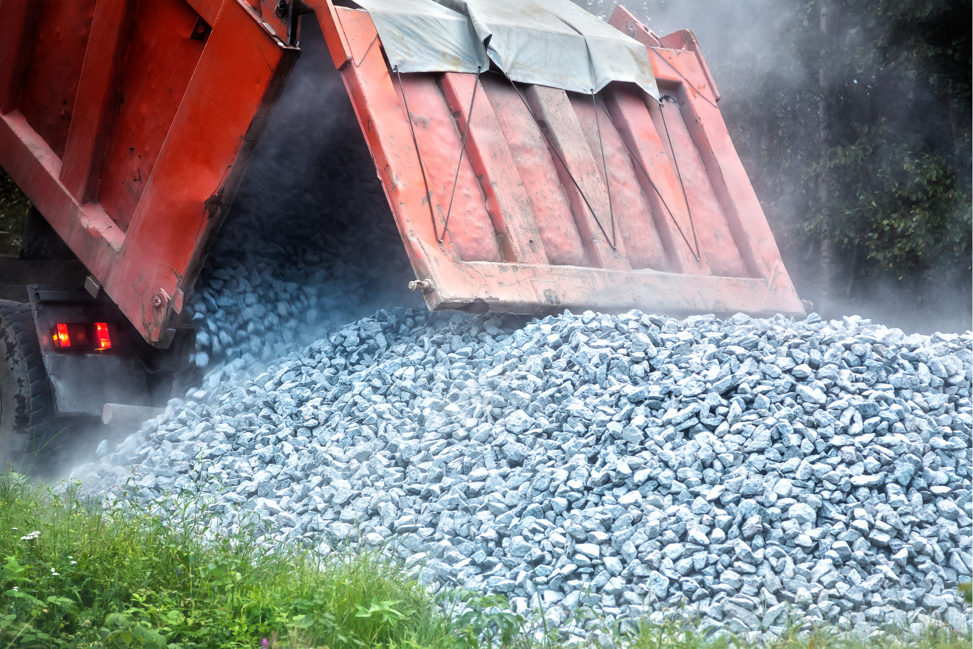 A dump truck is loading gravel into a pile.