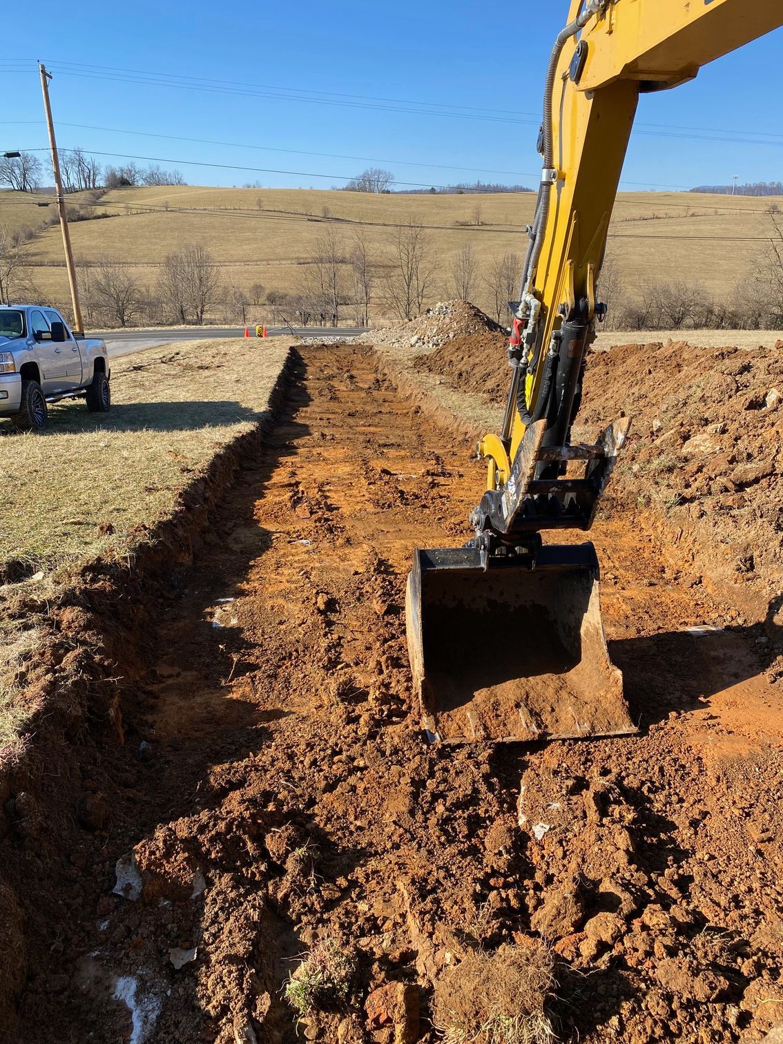 A yellow excavator is digging a hole in the dirt.