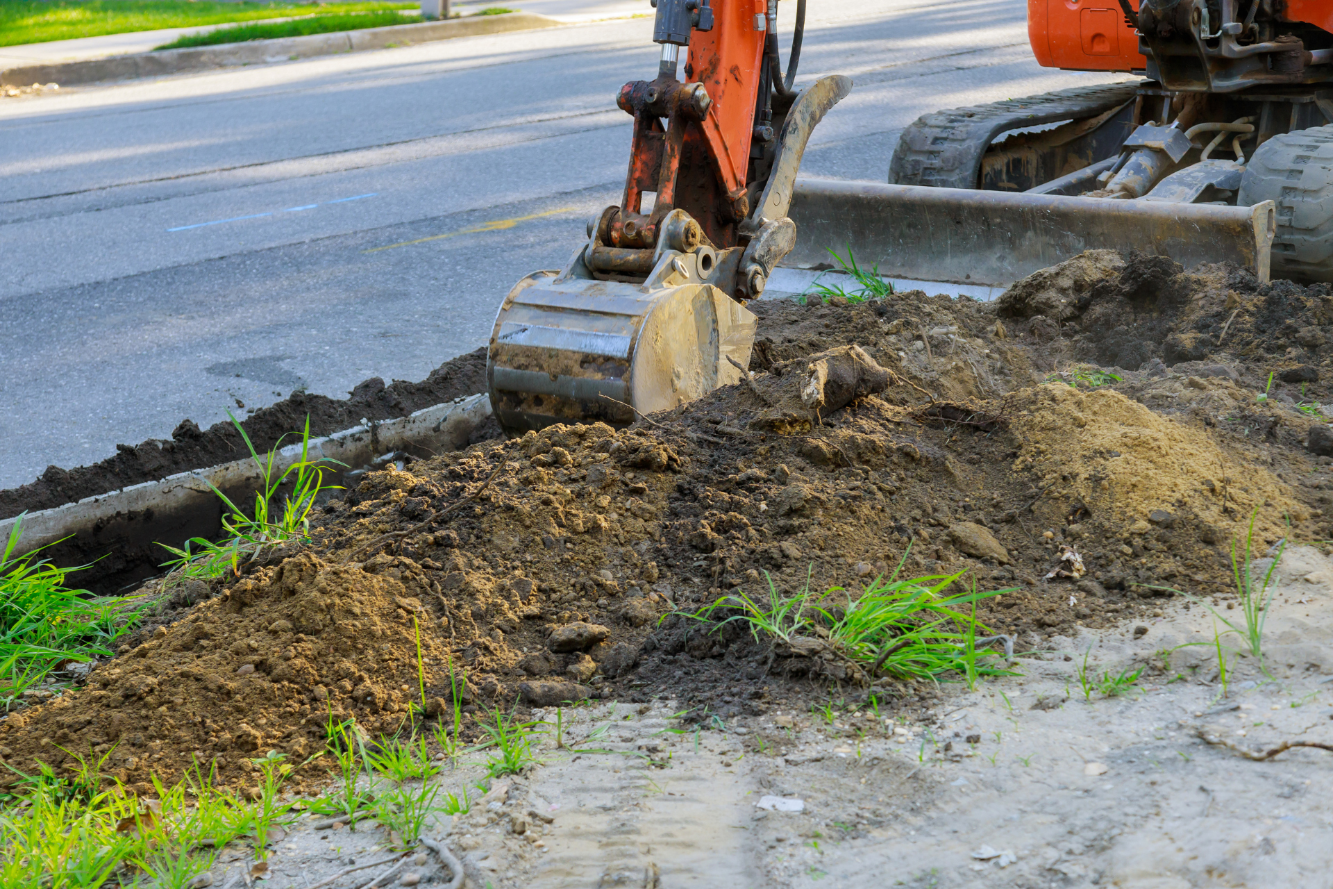 A bulldozer is digging a hole in the ground next to a road.