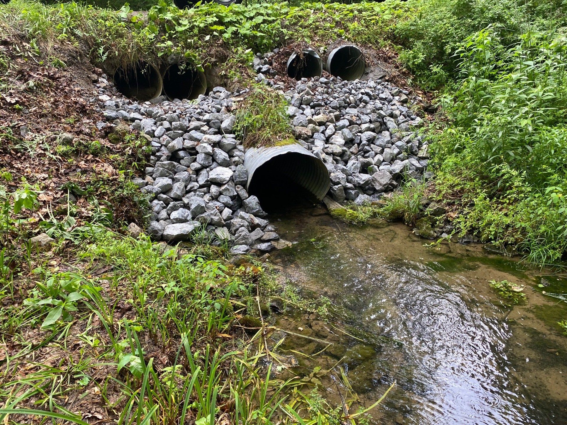 A river with a lot of rocks and pipes coming out of it.