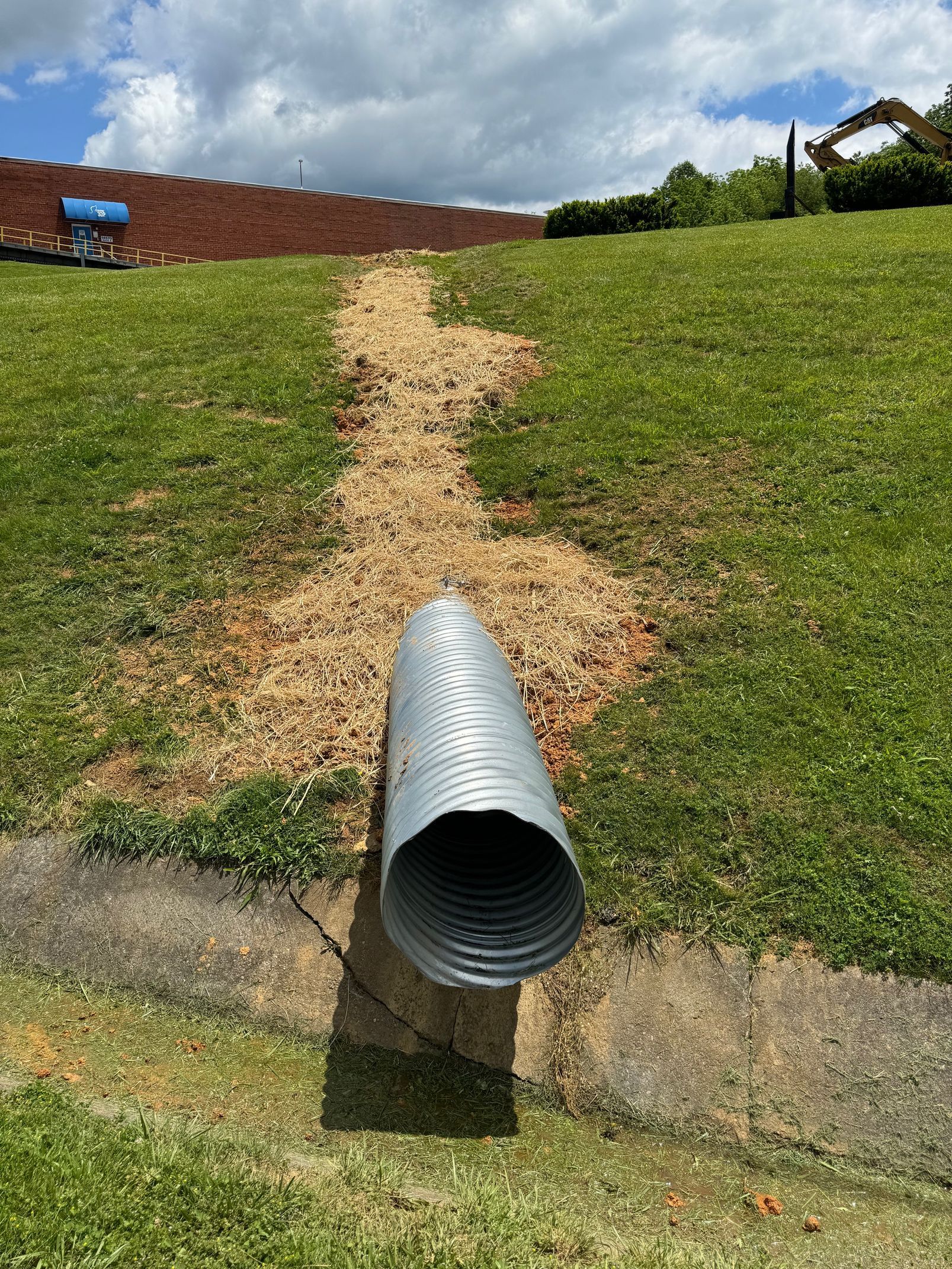 A large metal pipe is sitting in the middle of a grassy field.
