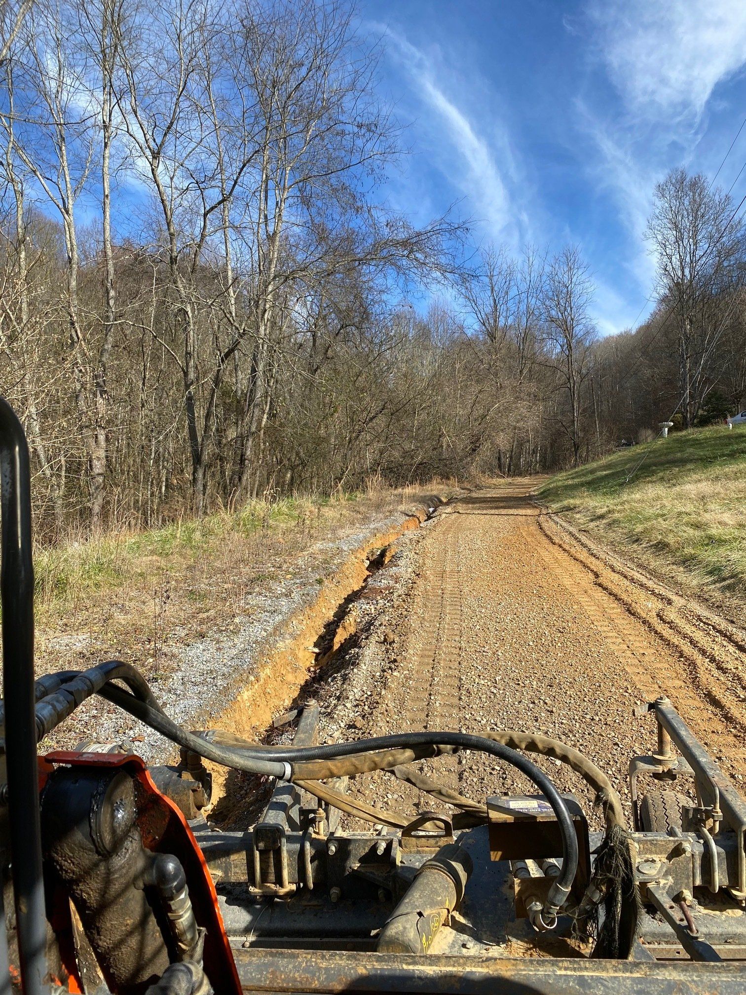 A person is driving a bulldozer down a dirt road.