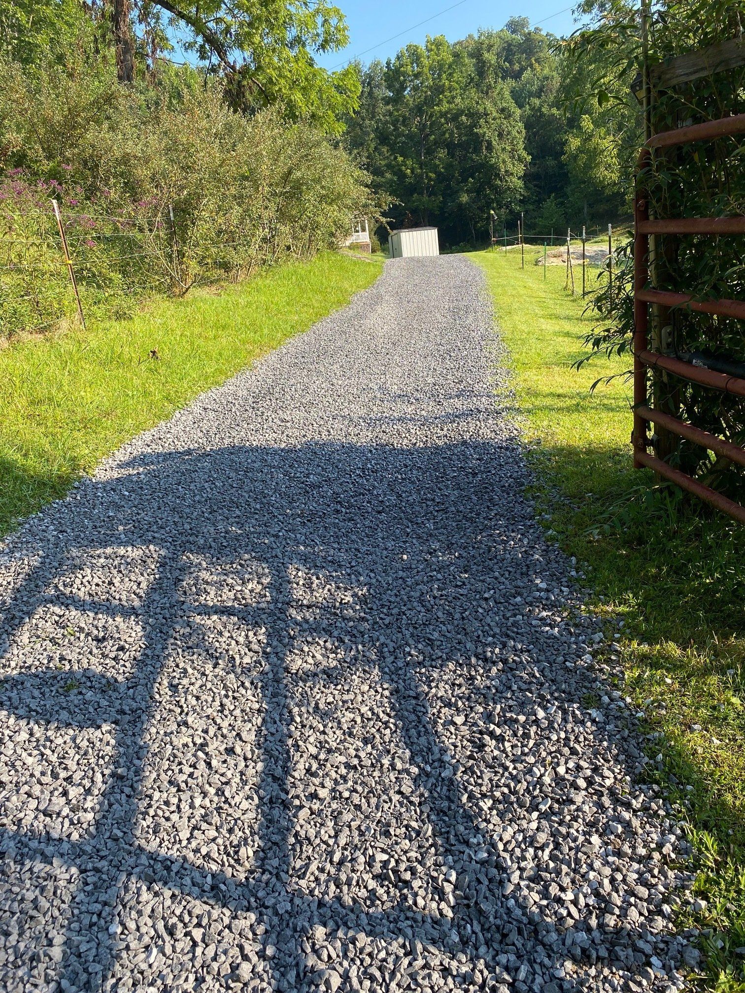 A gravel road going through a grassy field.