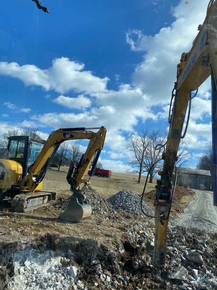 Two excavators are working in a dirt field.