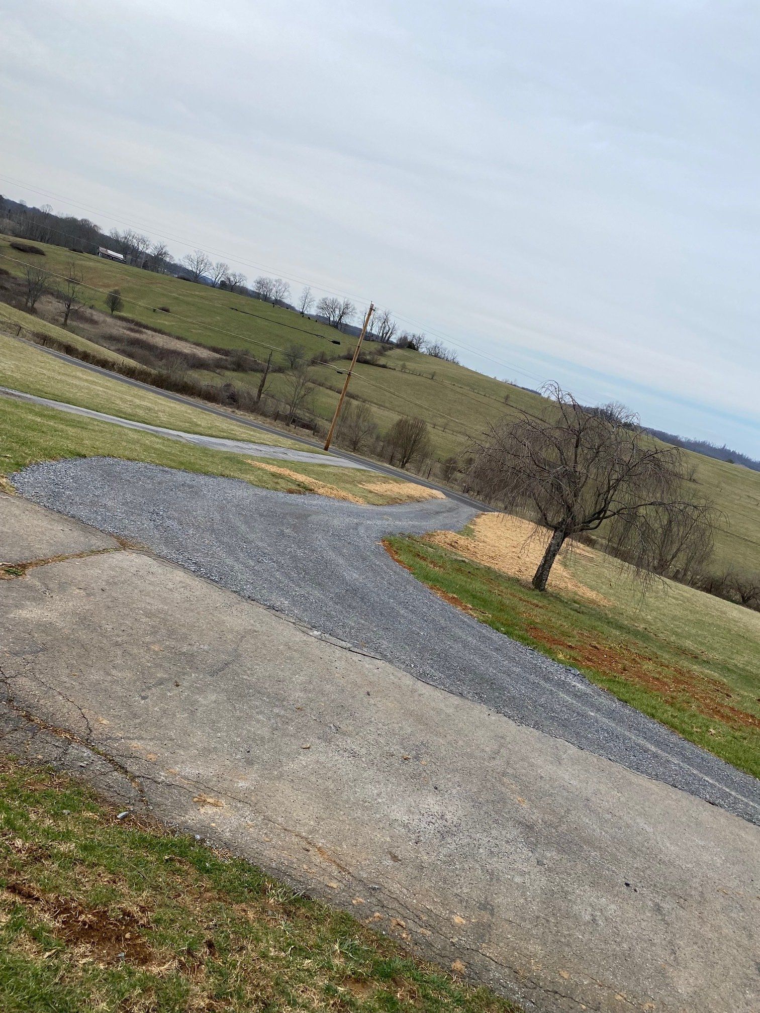 A gravel road going through a grassy hillside.