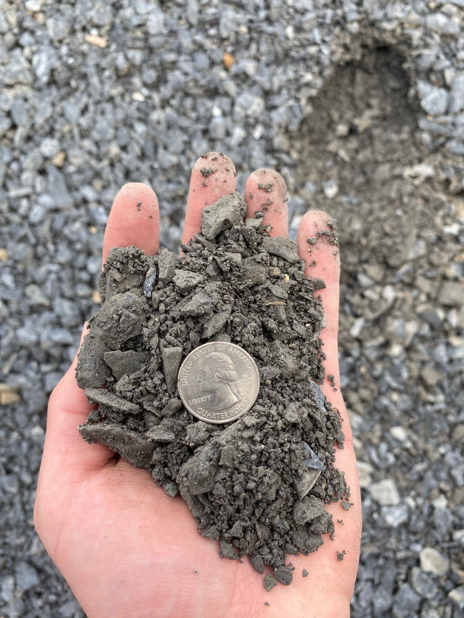 Crusher Run-3/4 Inch To Dust with aggregate in hand with a quarter to show sizing