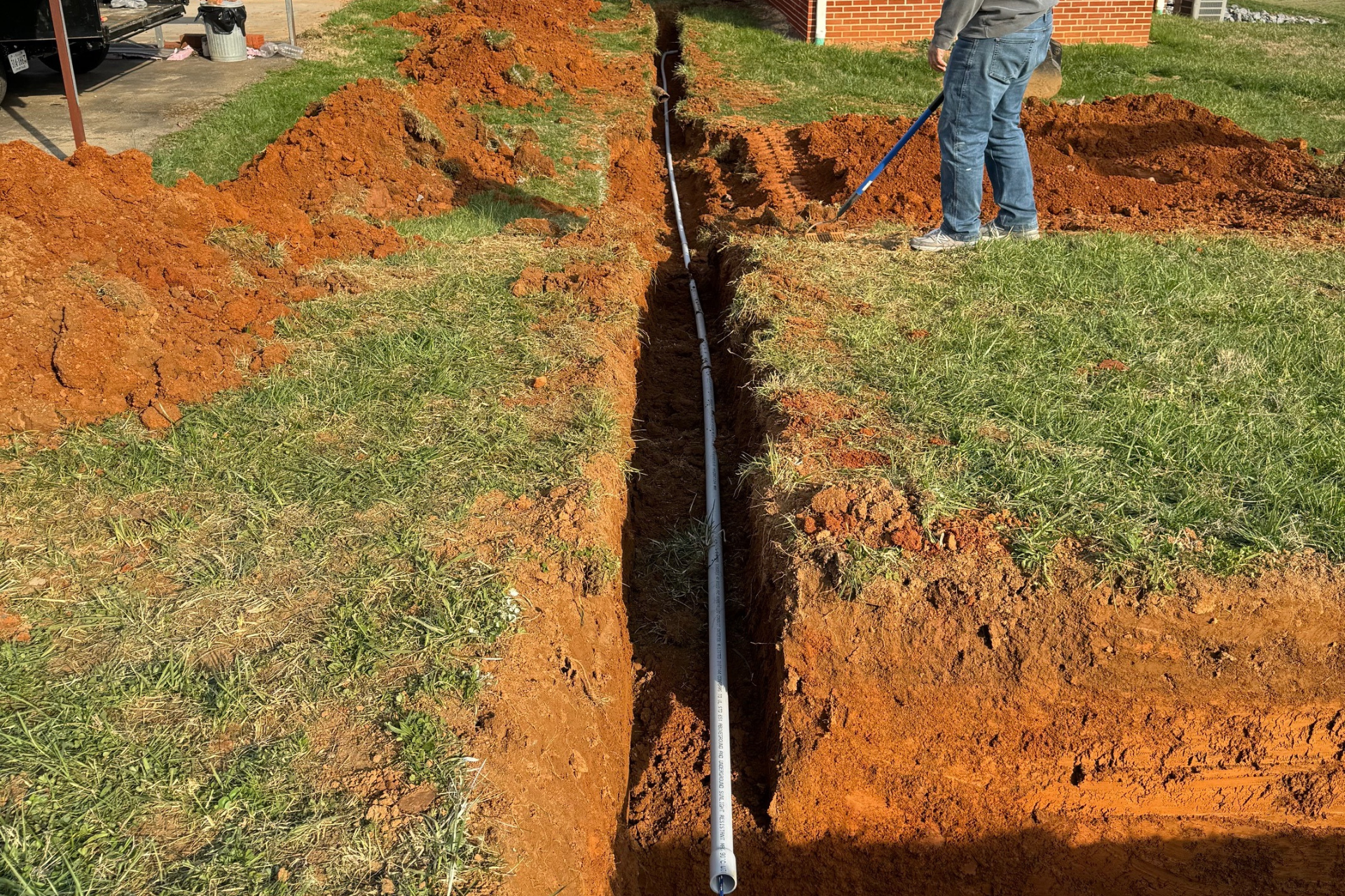 A man is digging a hole in the ground to install a pipe.