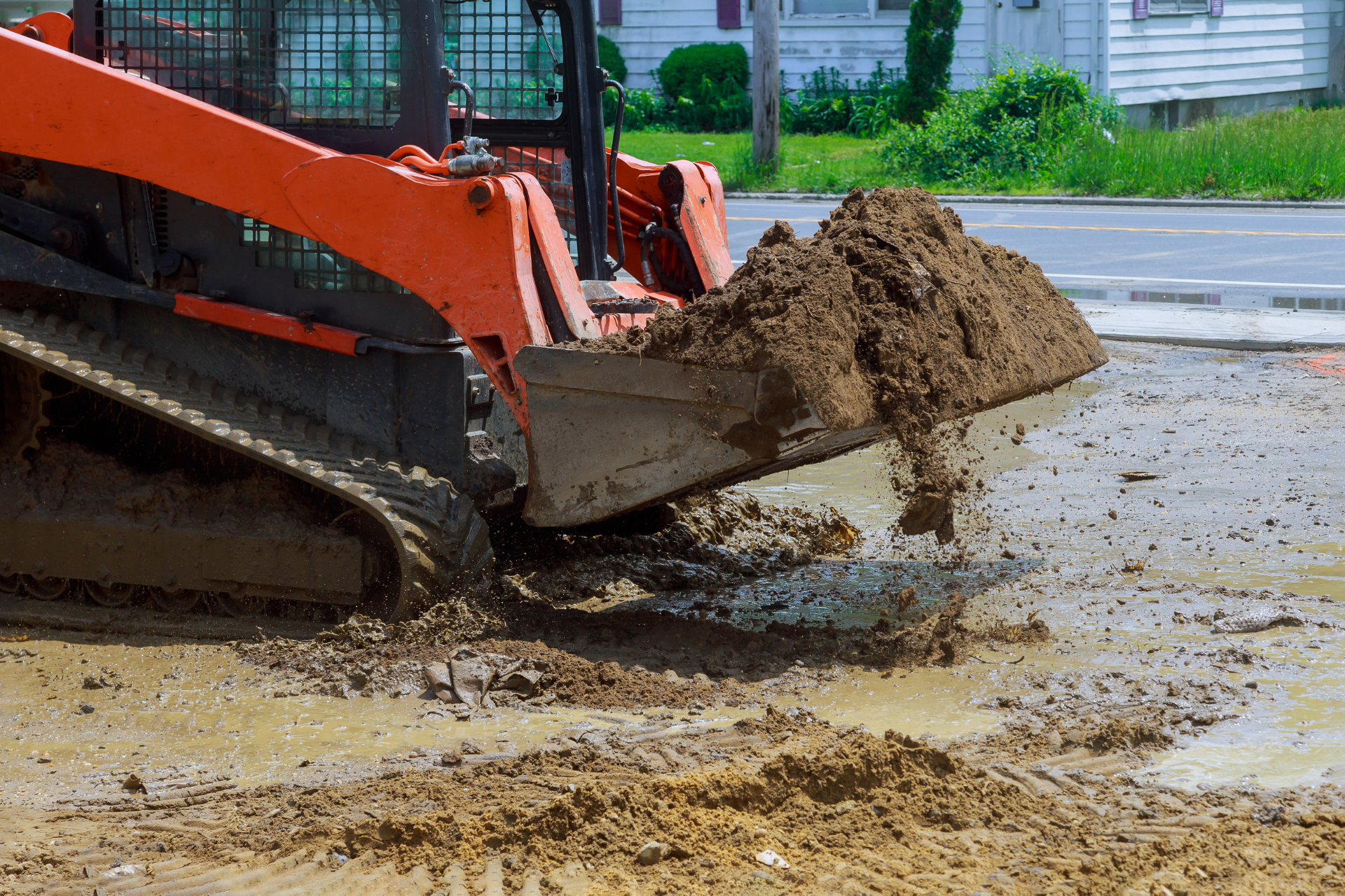 A bulldozer is scooping dirt out of a muddy field.