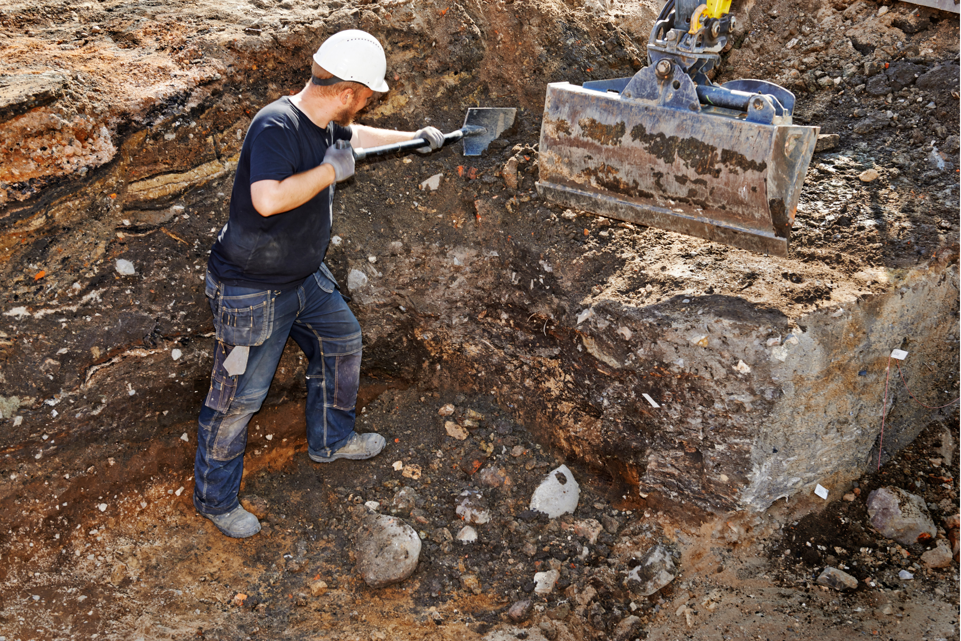 A man is digging in the dirt with a shovel.