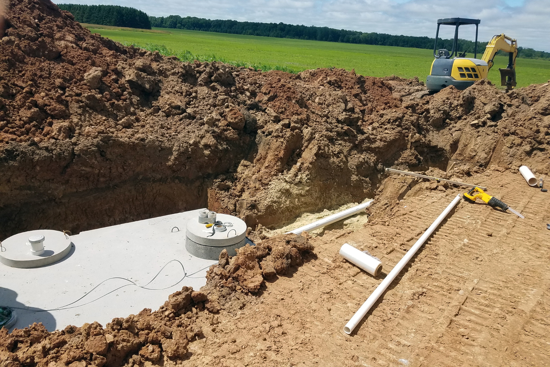 A man is working on a septic tank in the dirt.