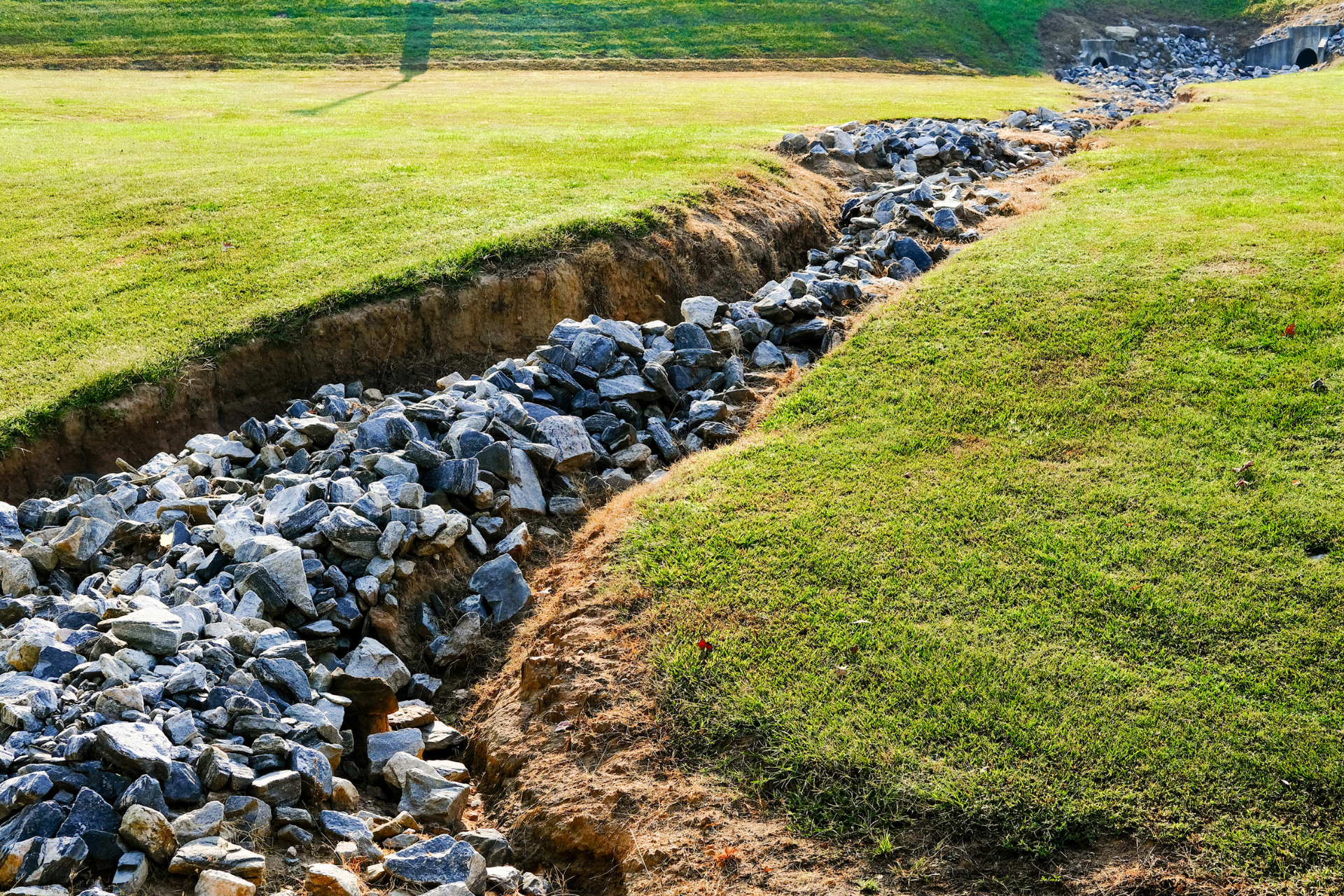 A stream of rocks is running through a grassy field.