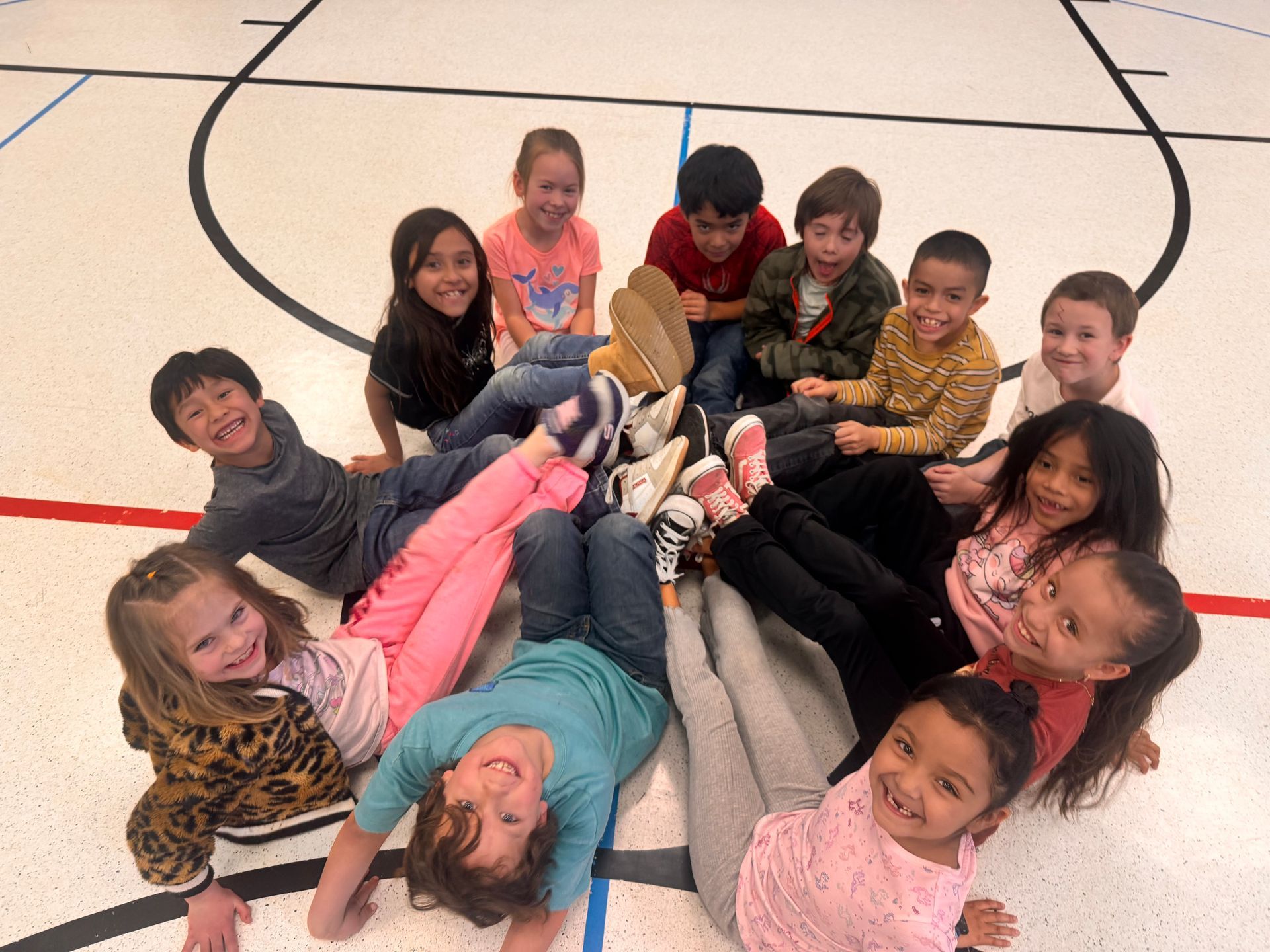 First grade students smiling while sitting on the ground in a circle.