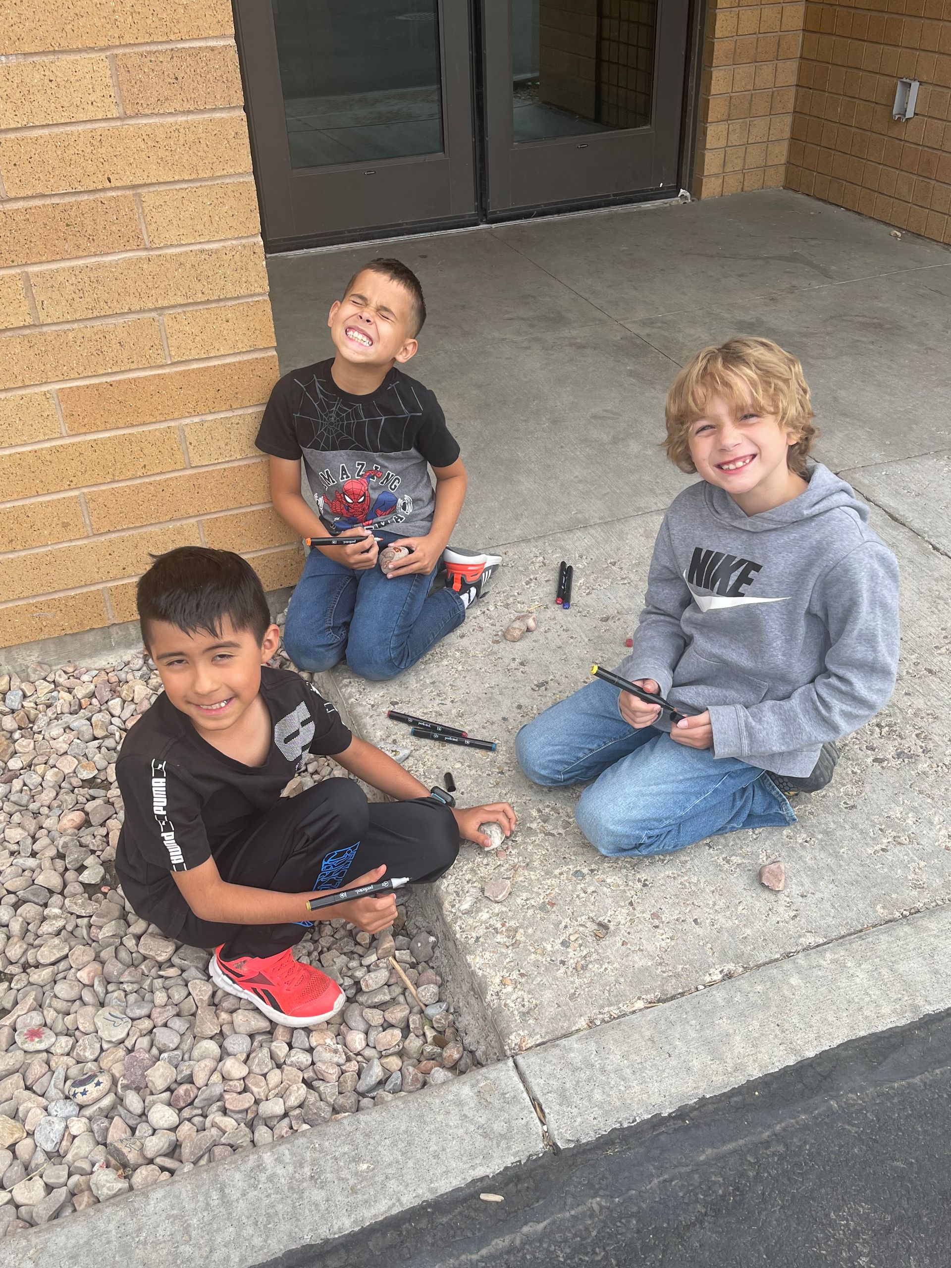 Students smiling while they paint rocks.