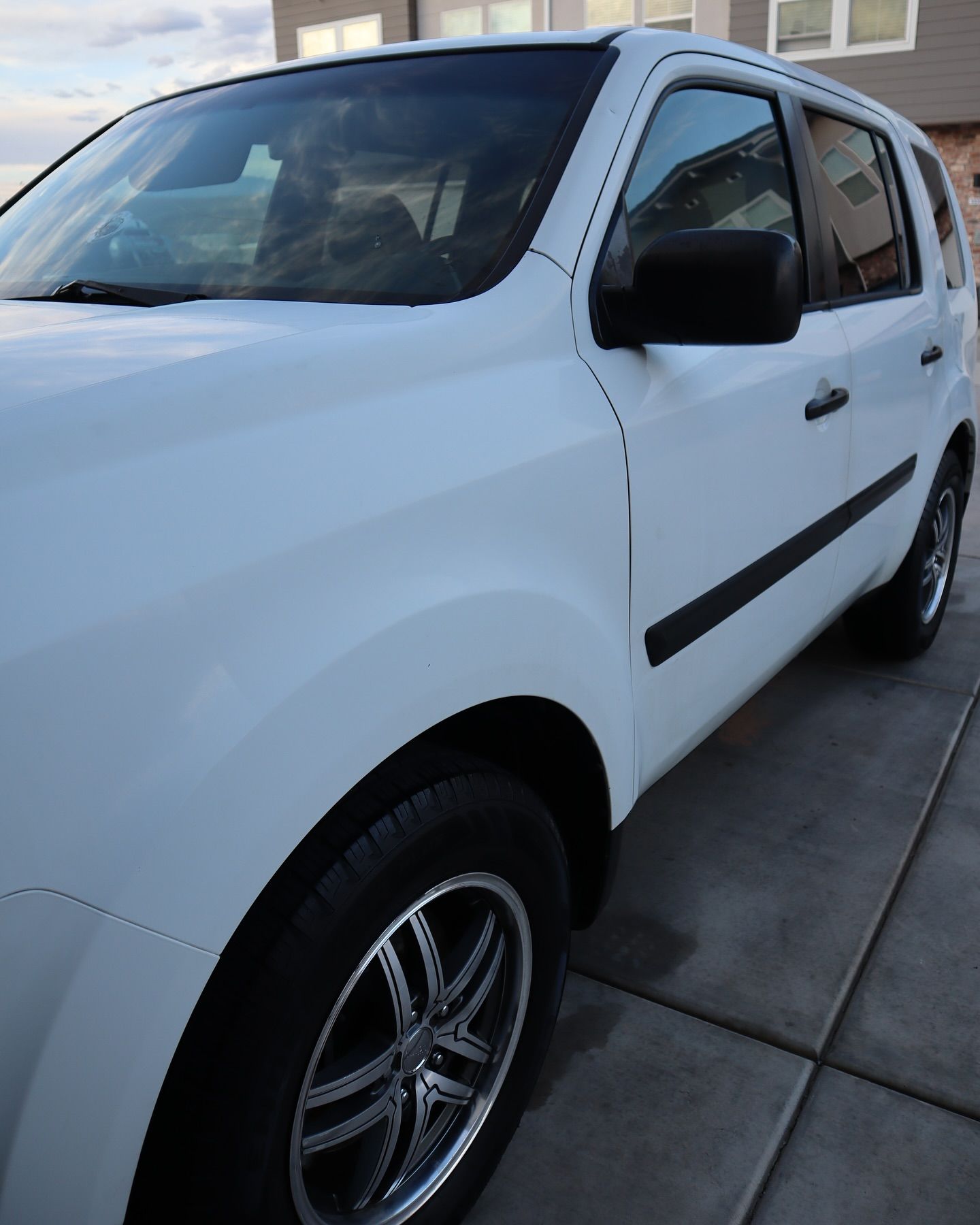 White SUV parked on a paved driveway with black side trim and chrome wheels.