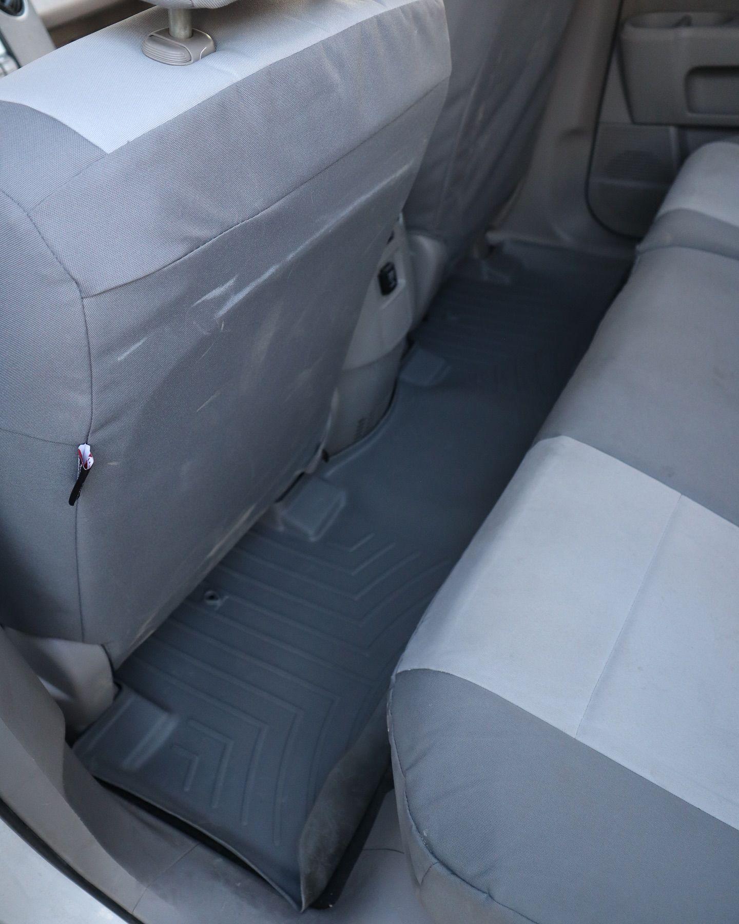 Gray car backseat with floor mat.