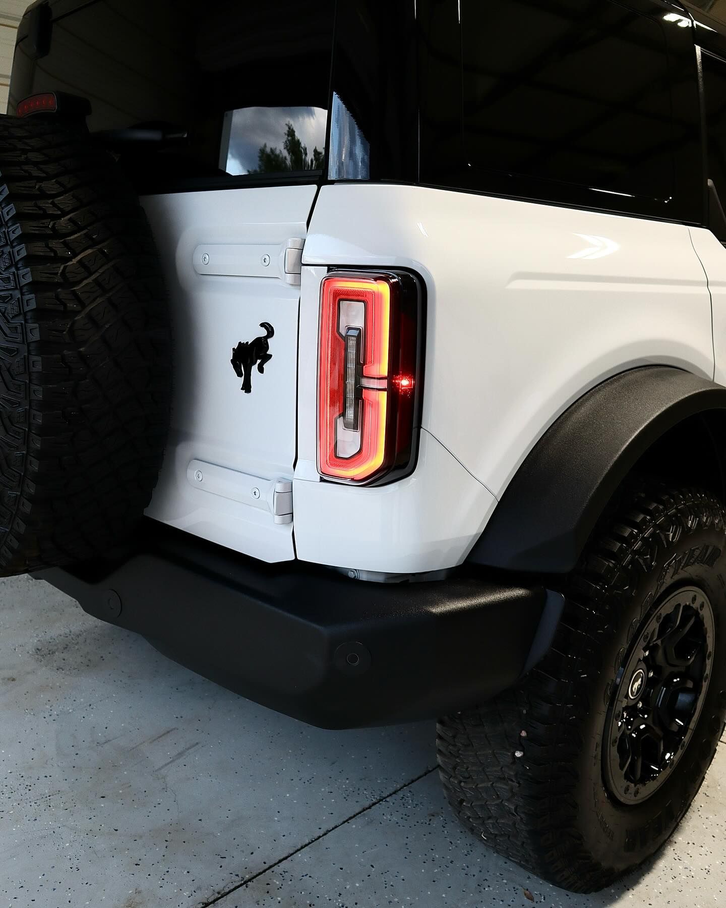 White Ford Bronco SUV rear view with black accents, spare tire, and taillight.