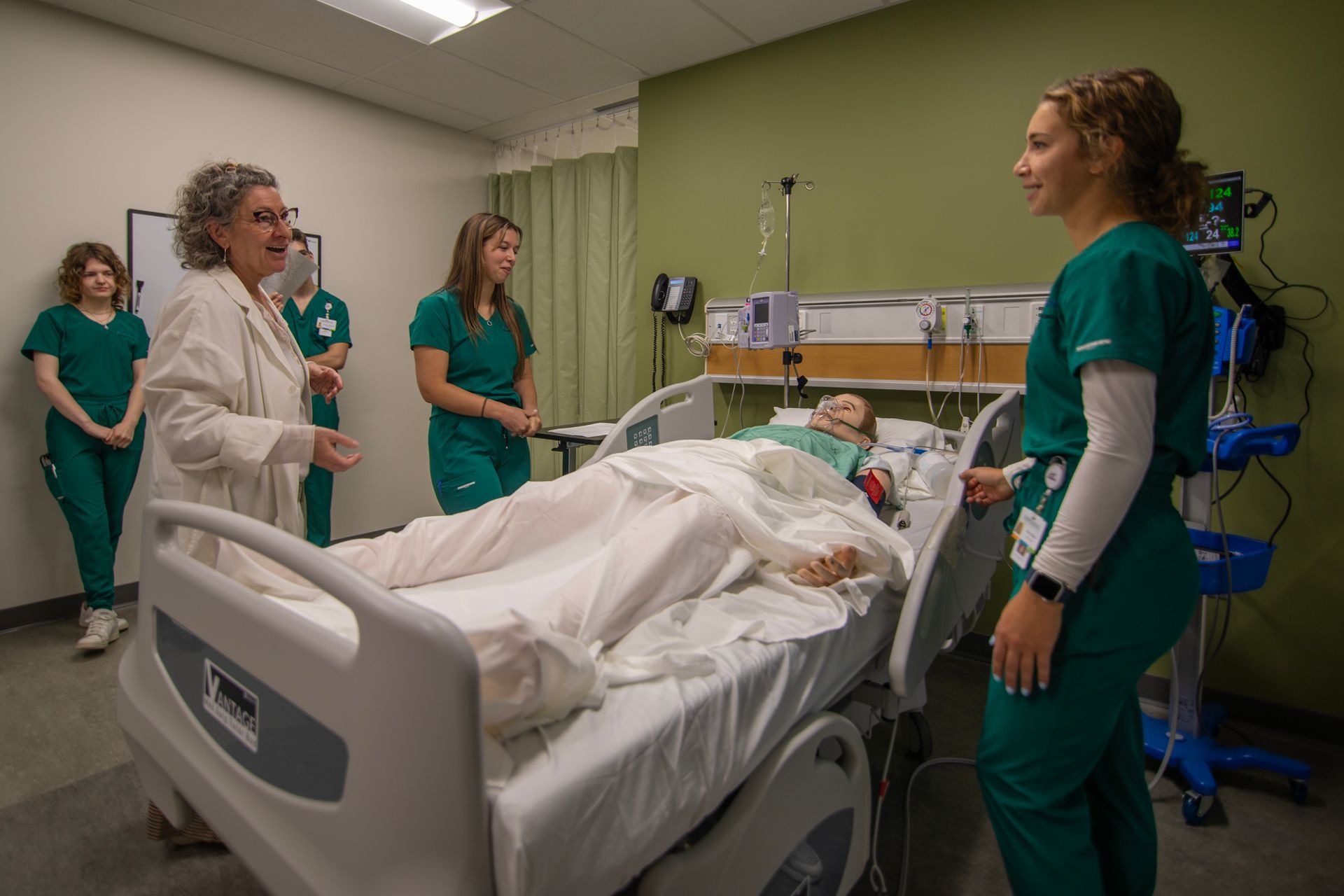 A group of nurses are standing around a patient in a hospital bed.