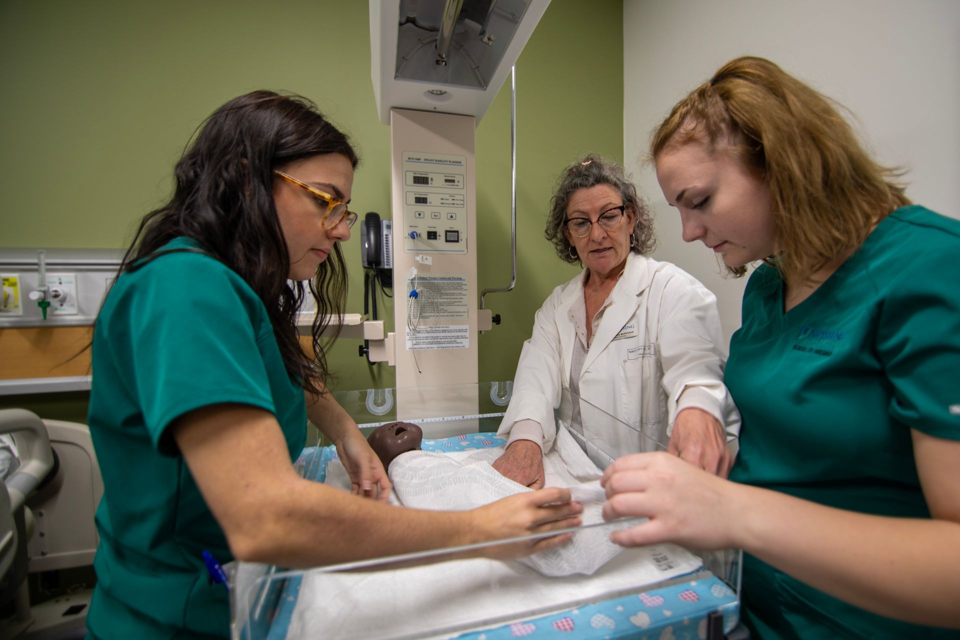 A group of nurses are working on a baby in a hospital room.