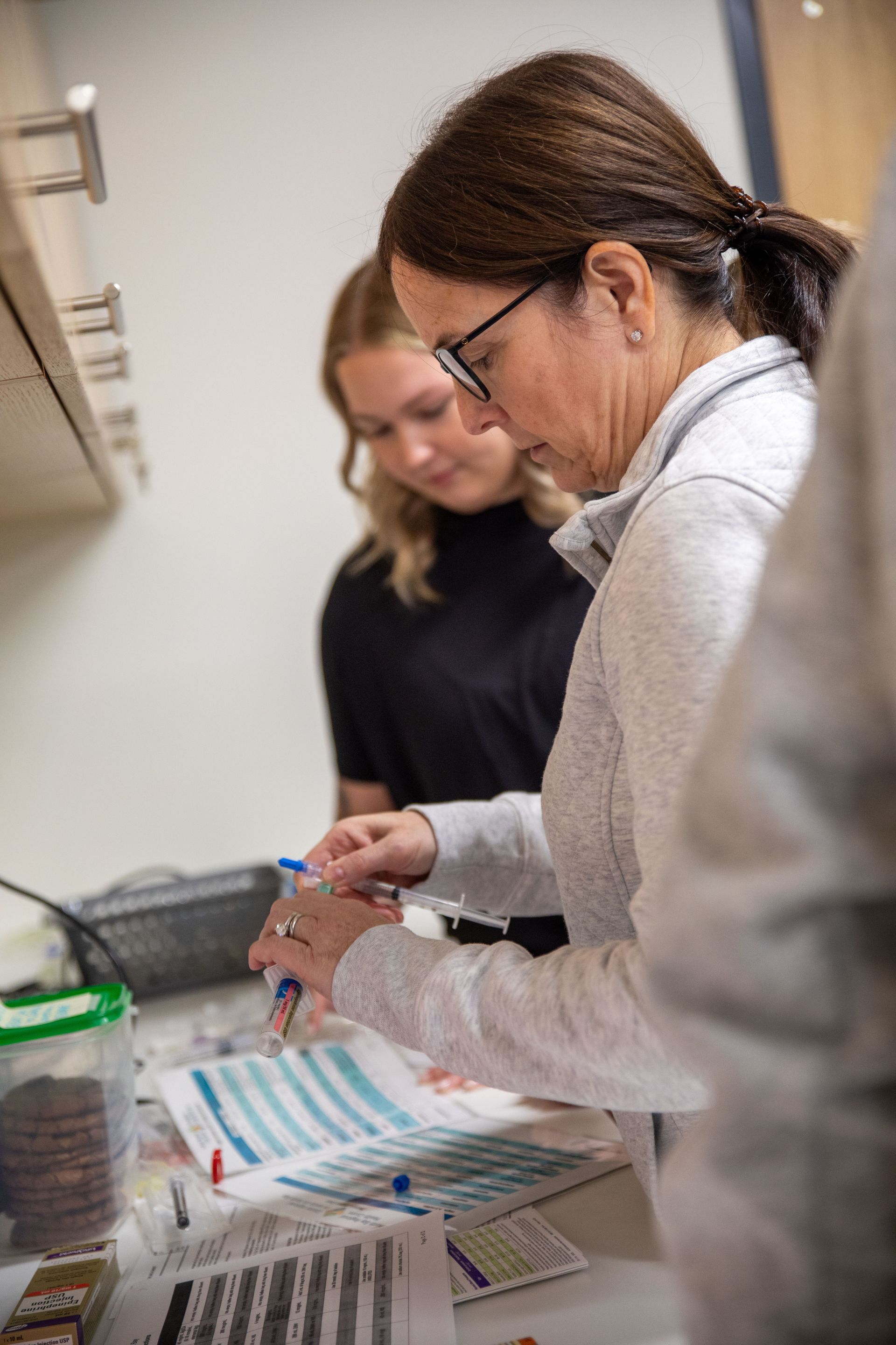 A woman is sitting at a table working on a piece of paper.