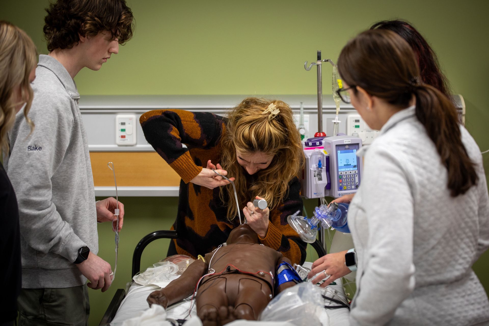 A group of people are working on a mannequin in a hospital room.