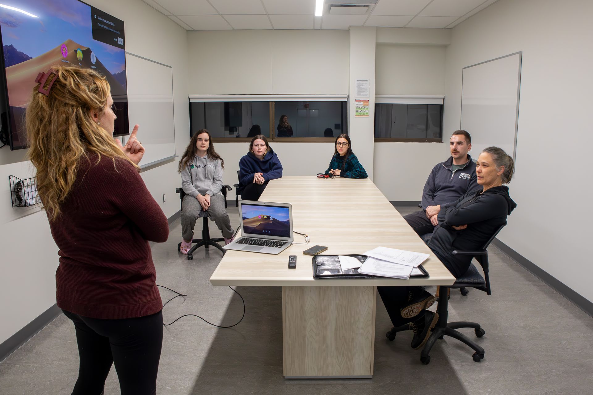 A woman is giving a presentation to a group of people in a conference room.