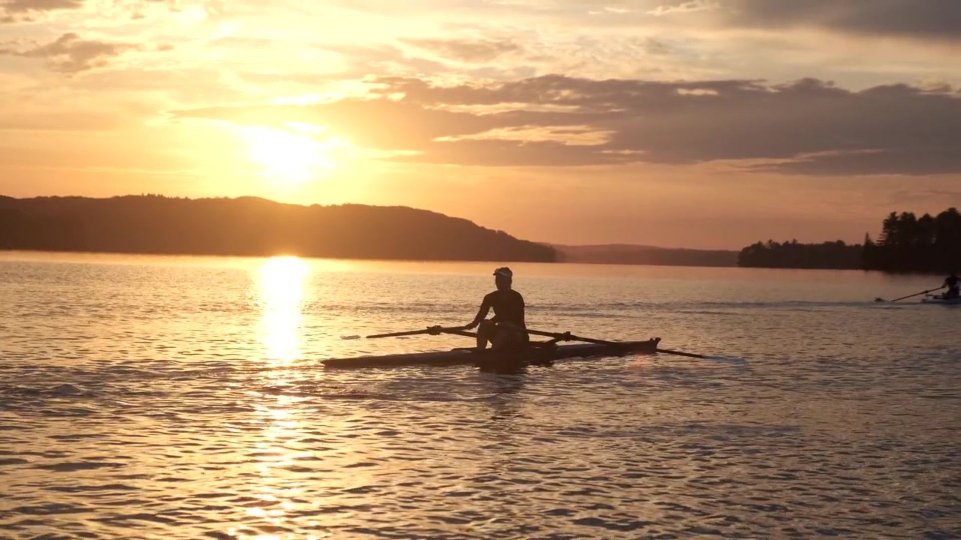 A person is rowing a boat on a lake at sunset