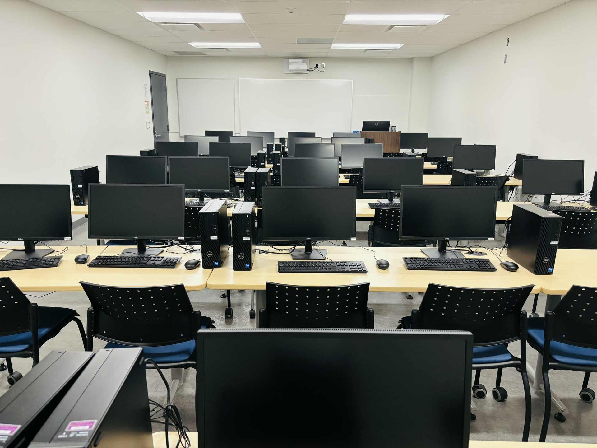 Computer lab with rows of desktops, chairs, and whiteboards.