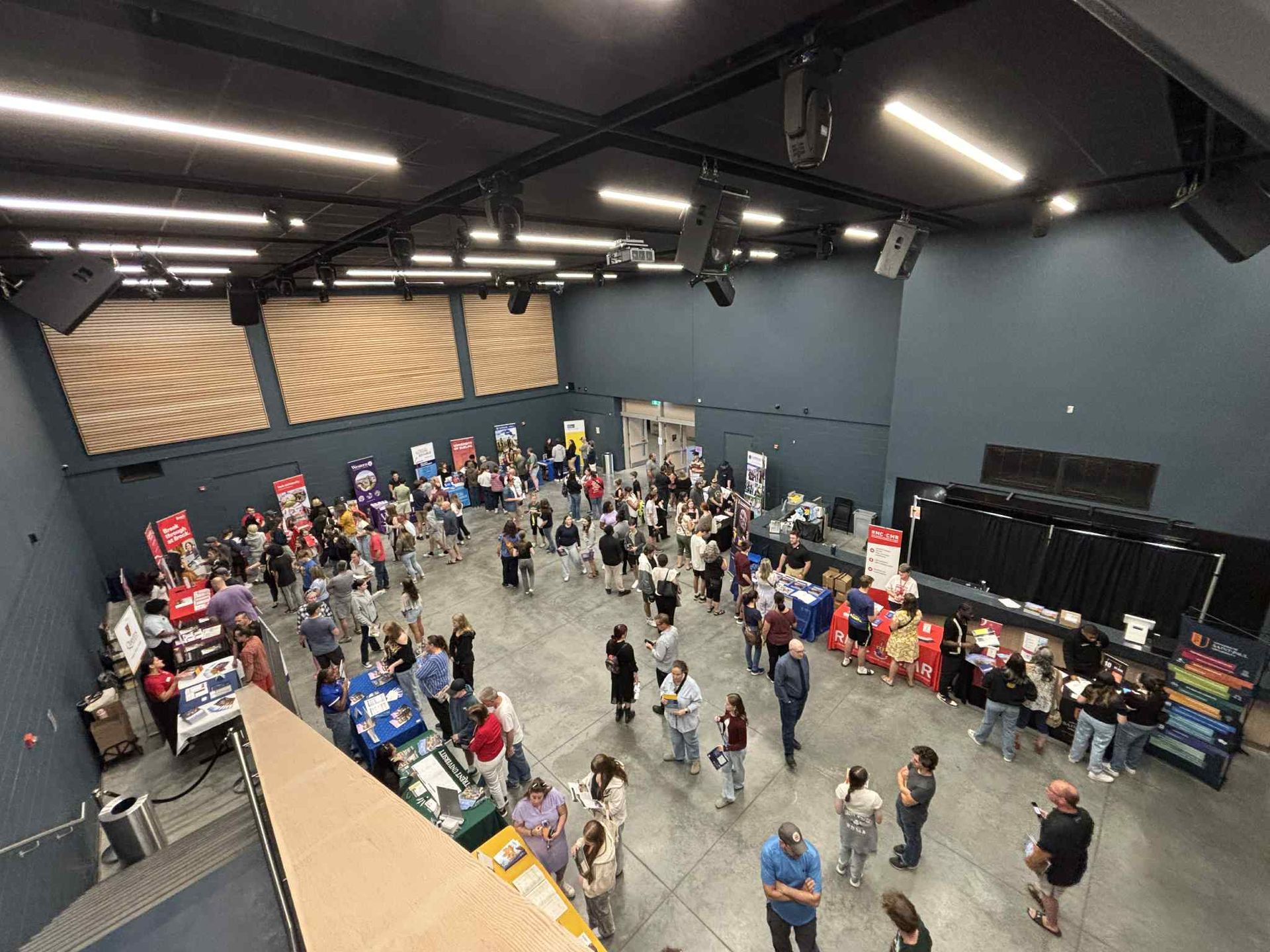 Cafeteria with orange chairs and tables, a bar area, and gray concrete flooring.