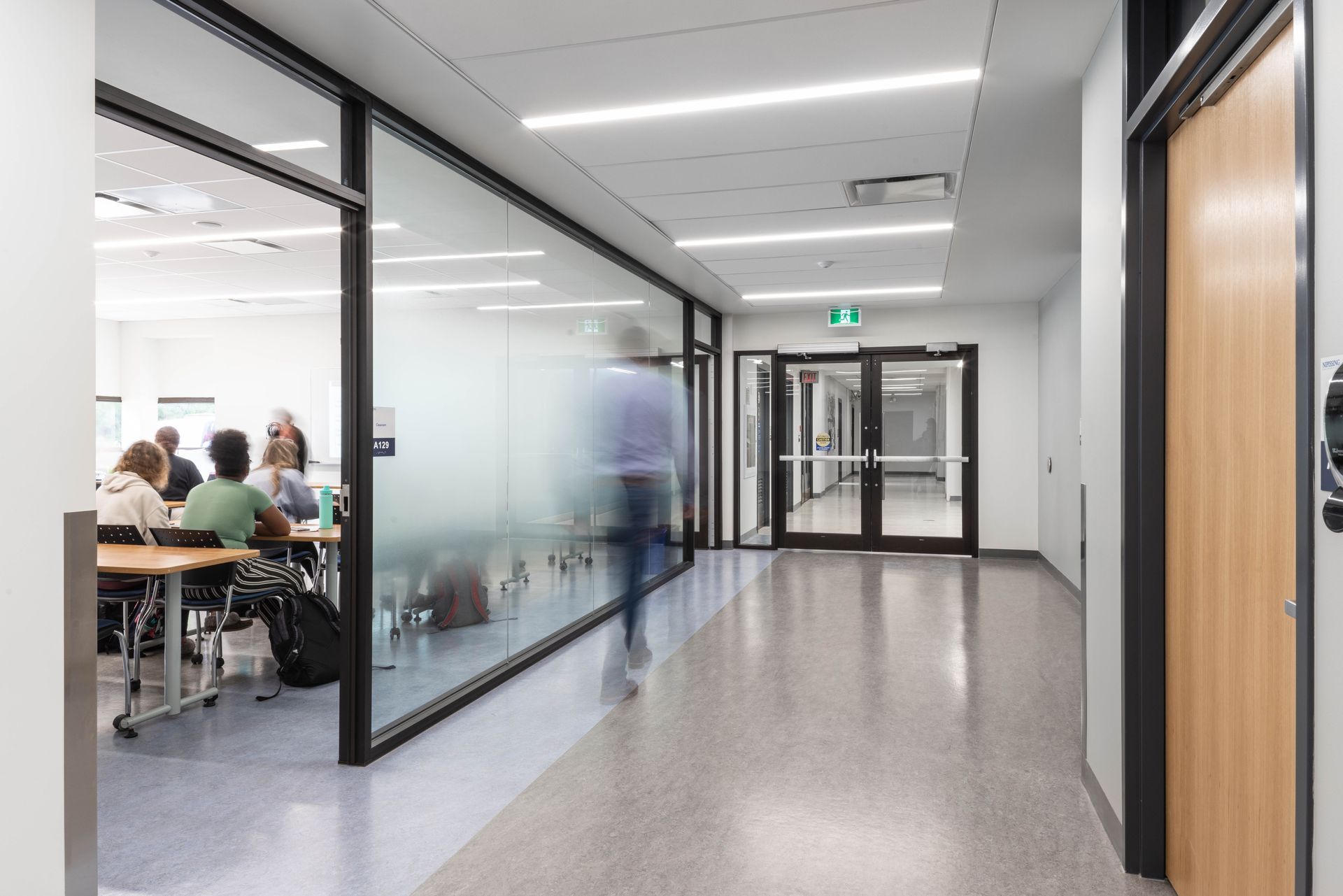 A group of people are sitting at tables in a hallway.