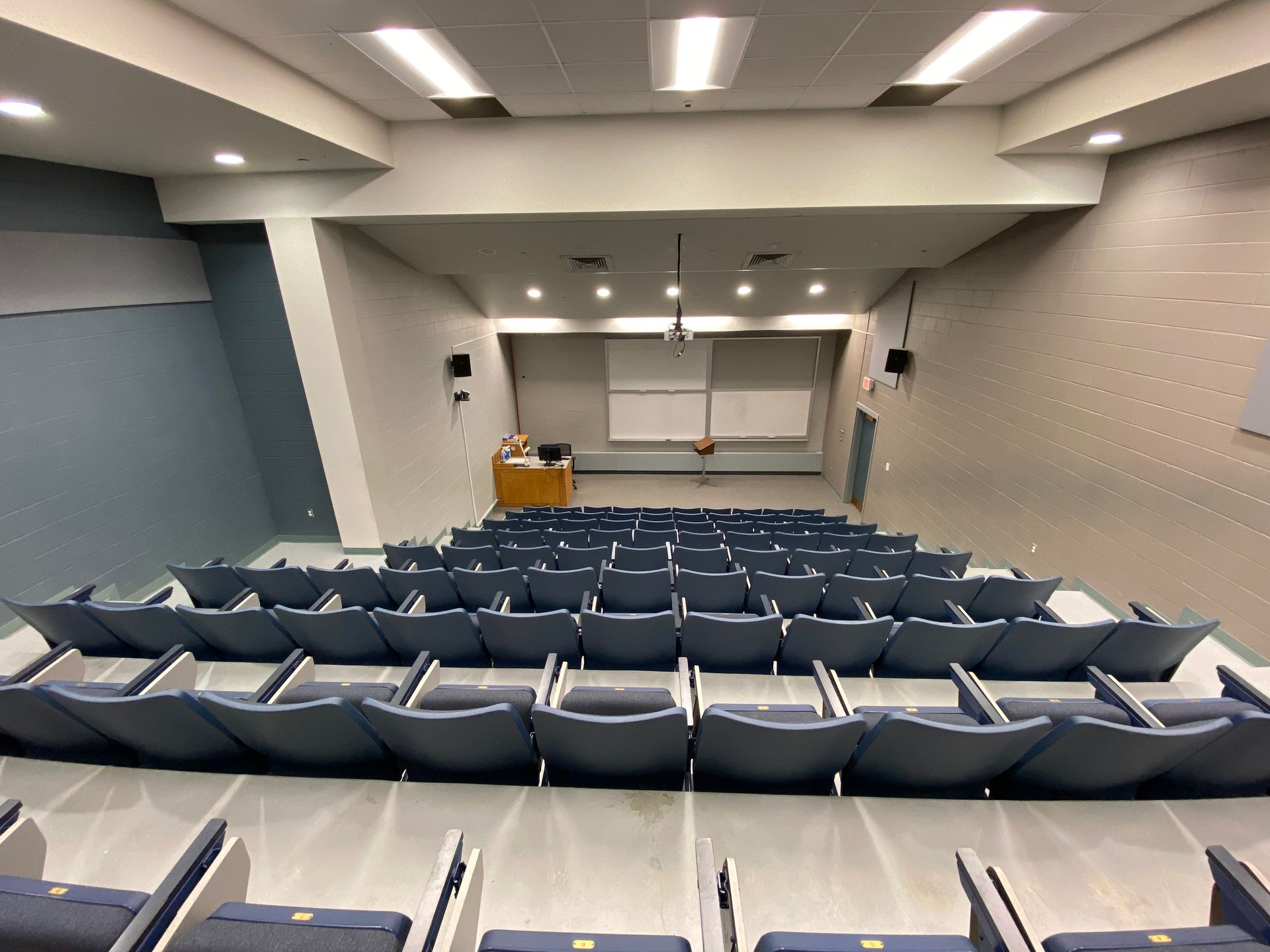 An auditorium with blue seats and a projector screen