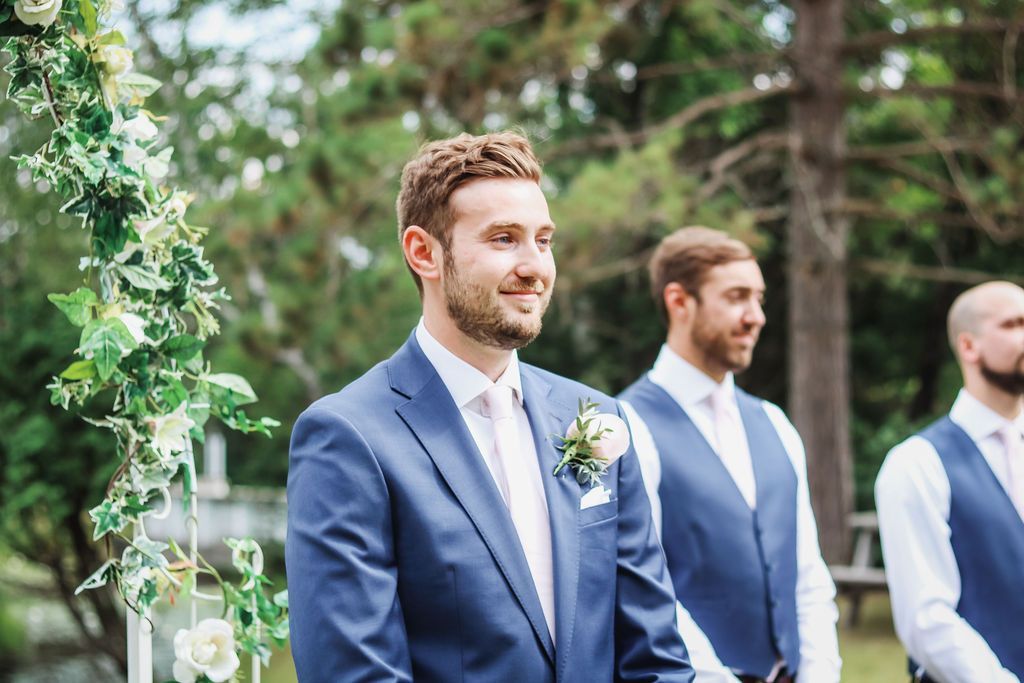 A groom and his groomsmen are waiting for the bride to walk down the aisle at a wedding.