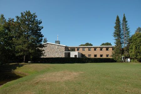 Stone and brick building with a lawn and trees on a sunny day.