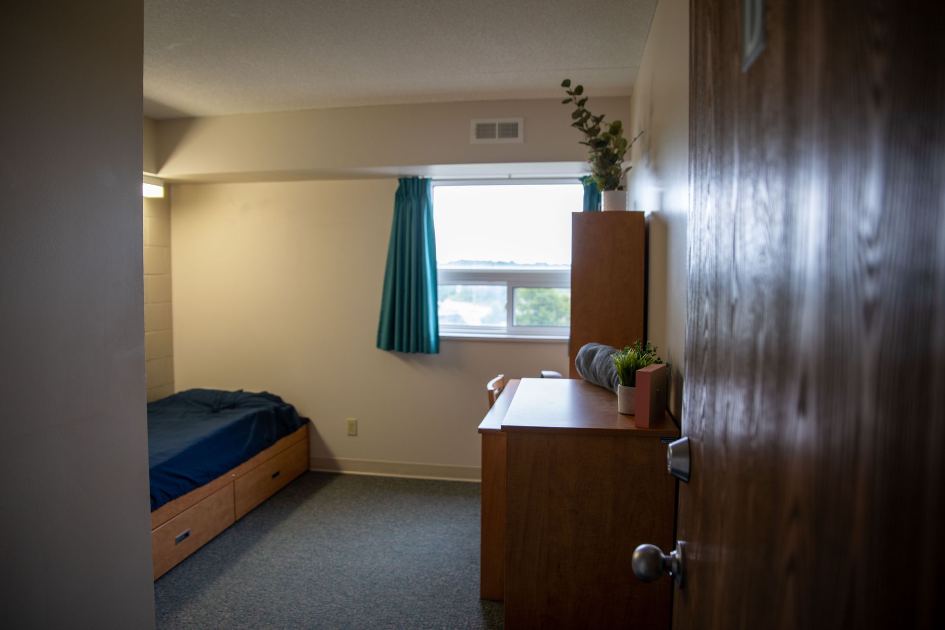 A bedroom with a bed , desk , and window.