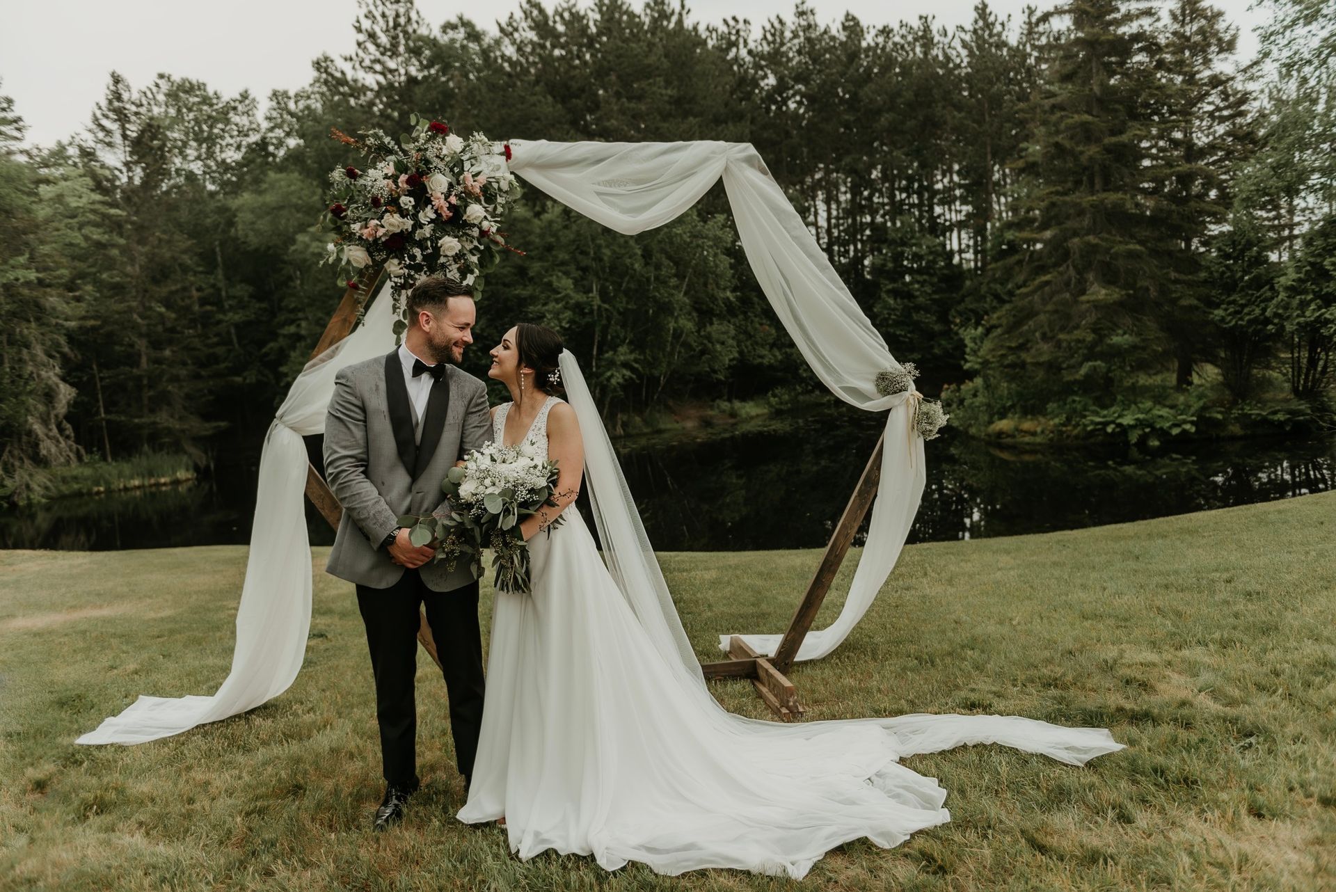 A bride and groom are posing for a picture in a field.