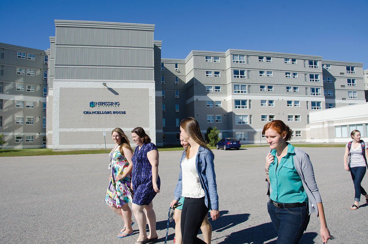 A group of women are walking in front of a large building