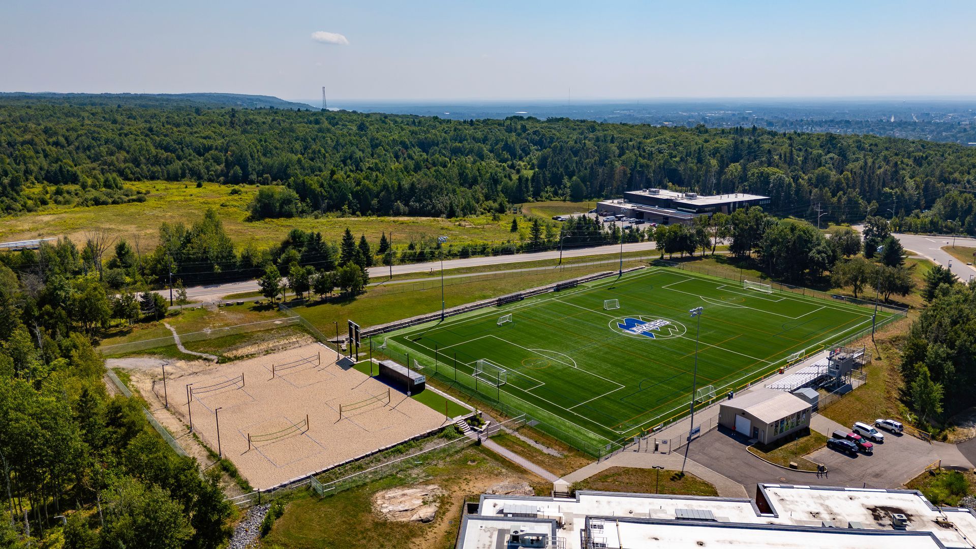 Interior of a modern building with large windows, wooden ceiling and accents, and linear lights.