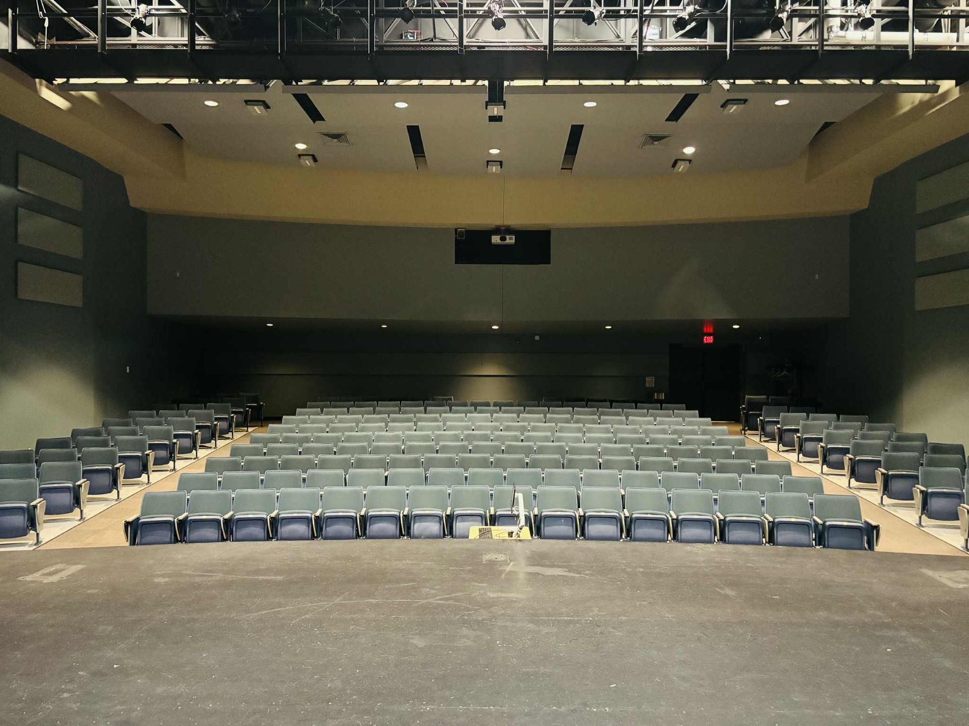 Conference room with blue table and chairs, large screens, and seating for a group.